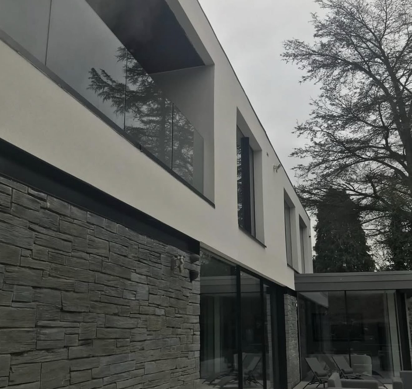 Contemporary elevation pairing smooth render above a stone-clad ground floor
