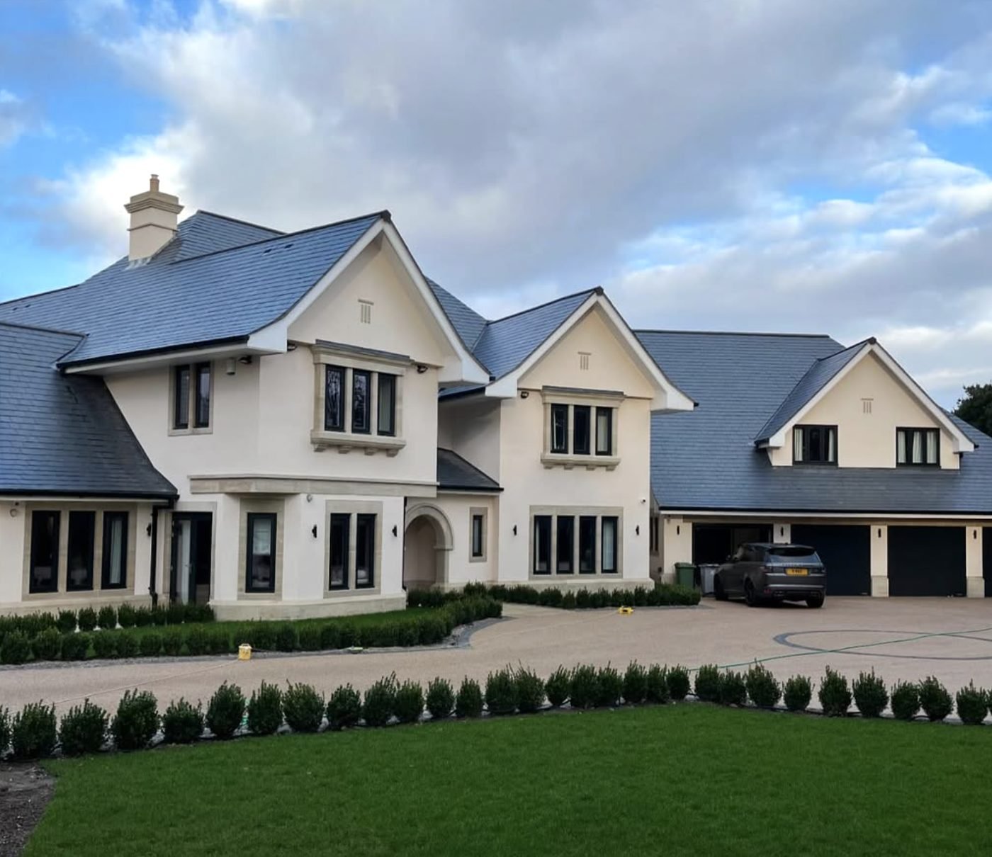 Substantial detached villa finished in a pale through-coloured render with dressed stone surrounds